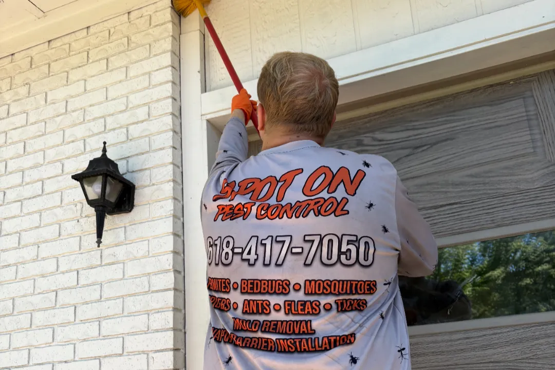 A Spot On technician treating the eaves of a brick home.